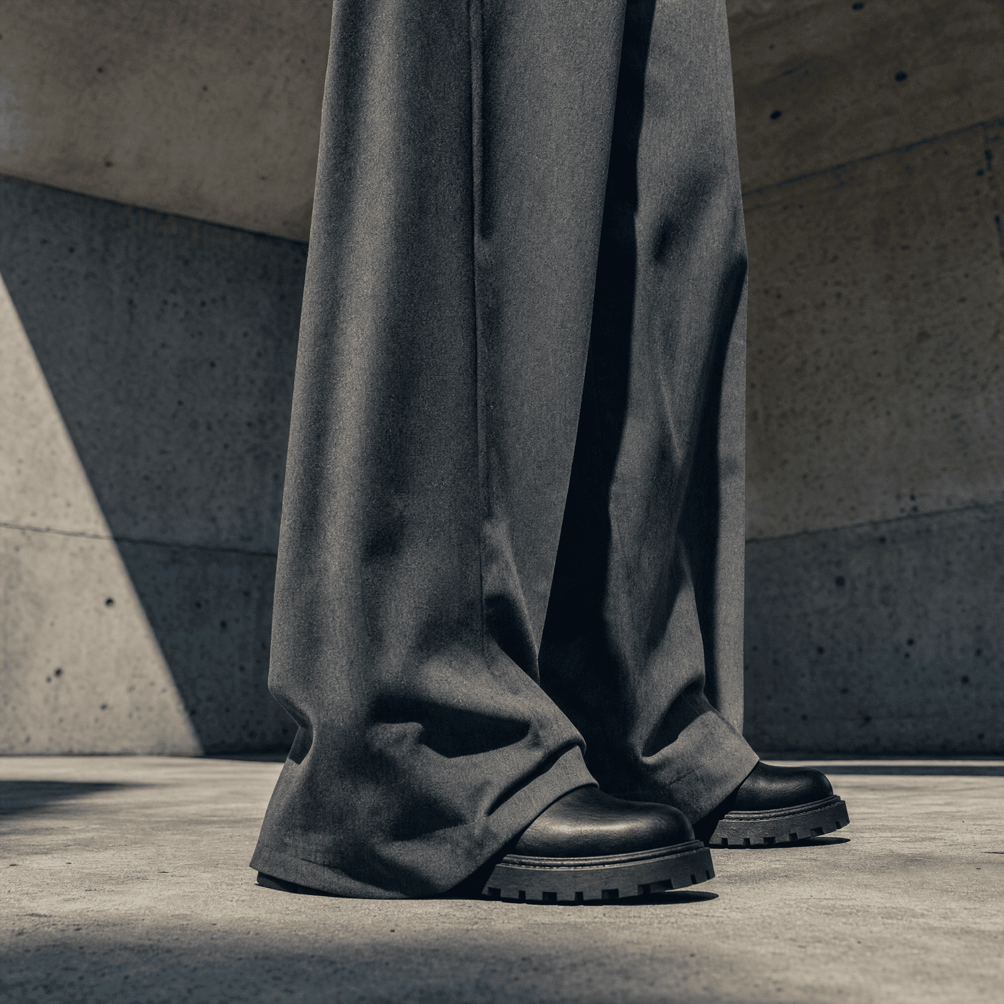 Low-angle crop of the wide heavyweight trouser breaking over leather footwear on concrete, Drop 04 editorial